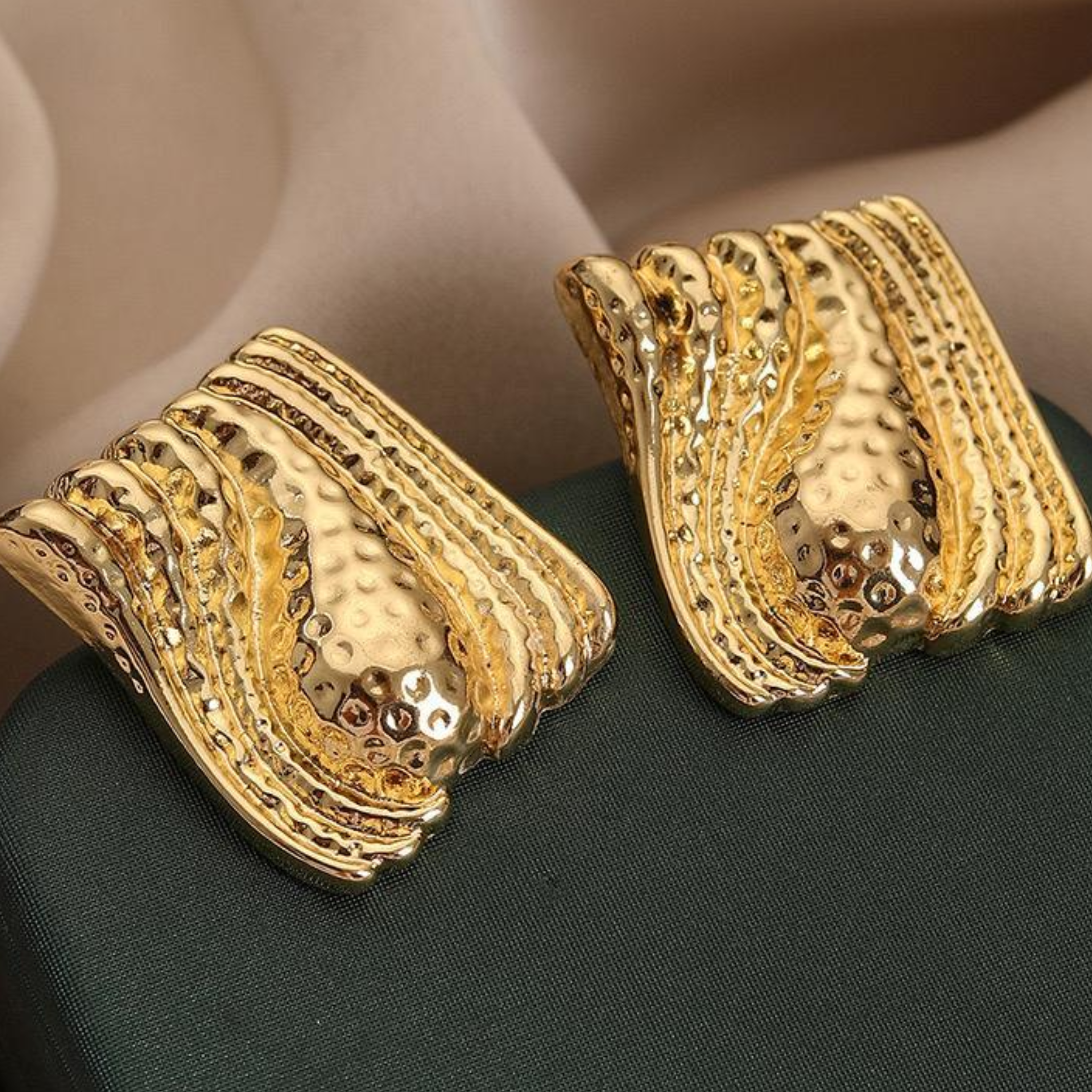 Gold earrings with intricate design on a dark surface