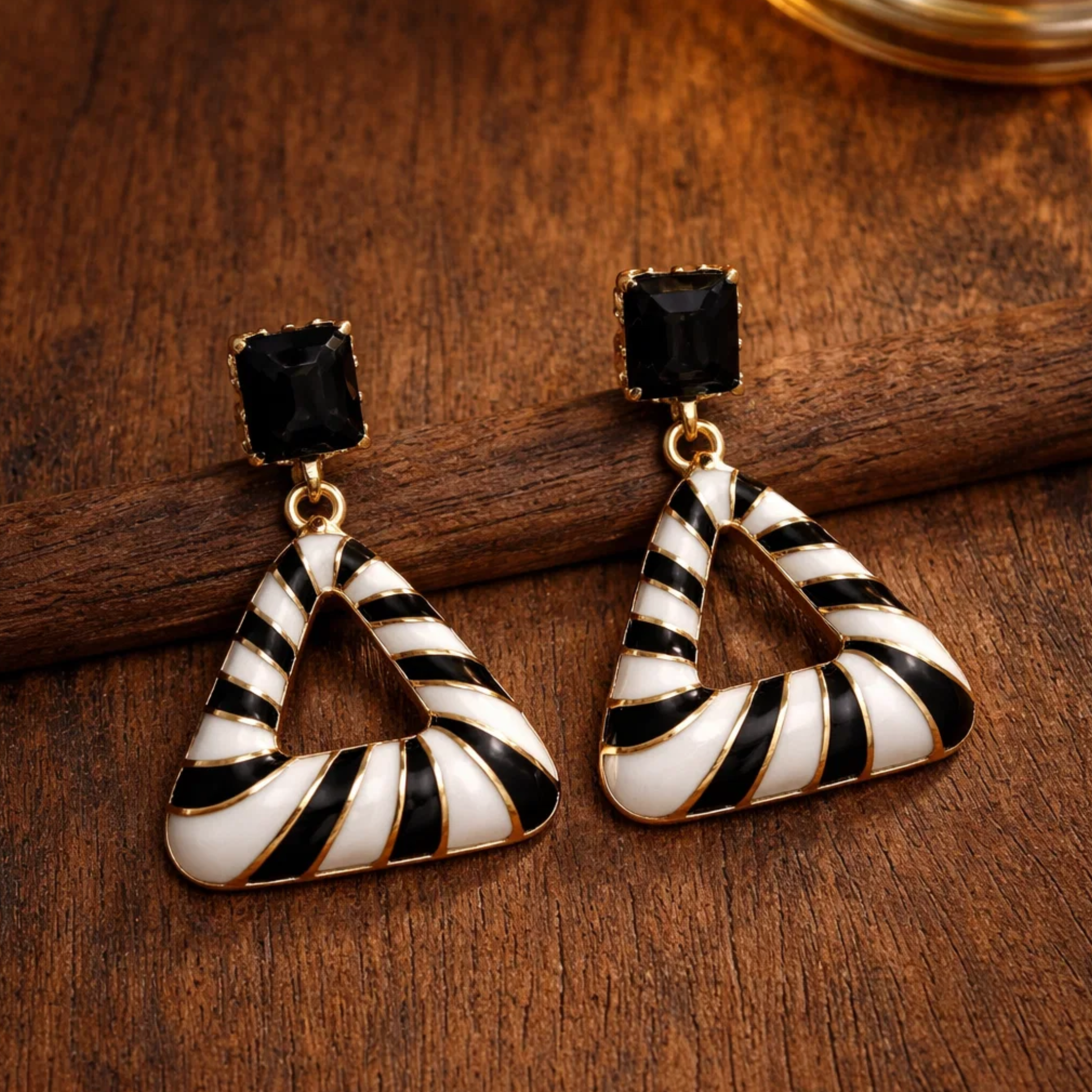 Triangular earrings with black and white striped design on a wooden surface