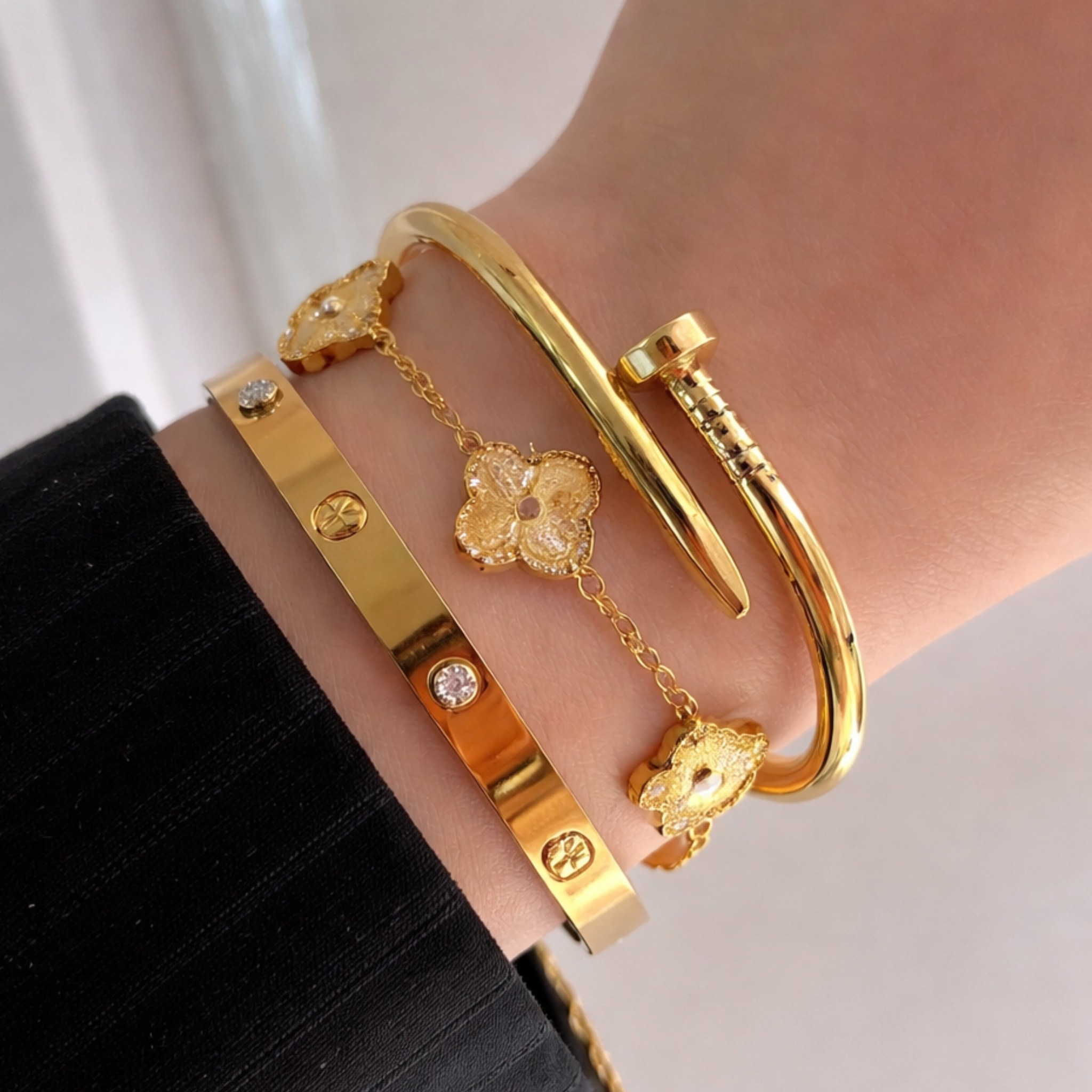 A woman wearing two bangles and one clover bracelet 