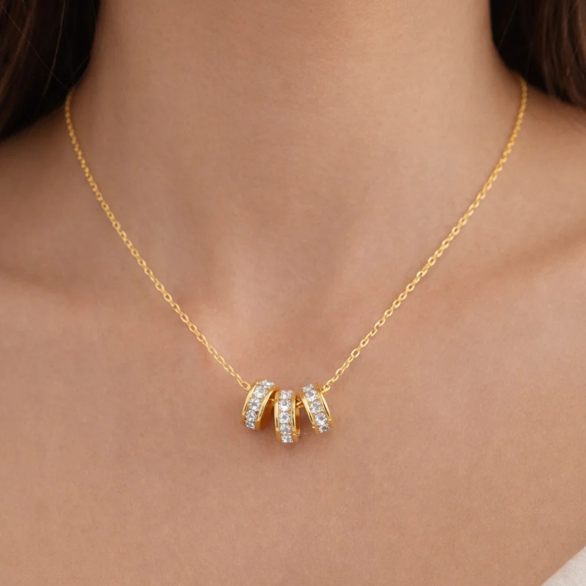Gold necklace with a diamond pendant on a person's neck
