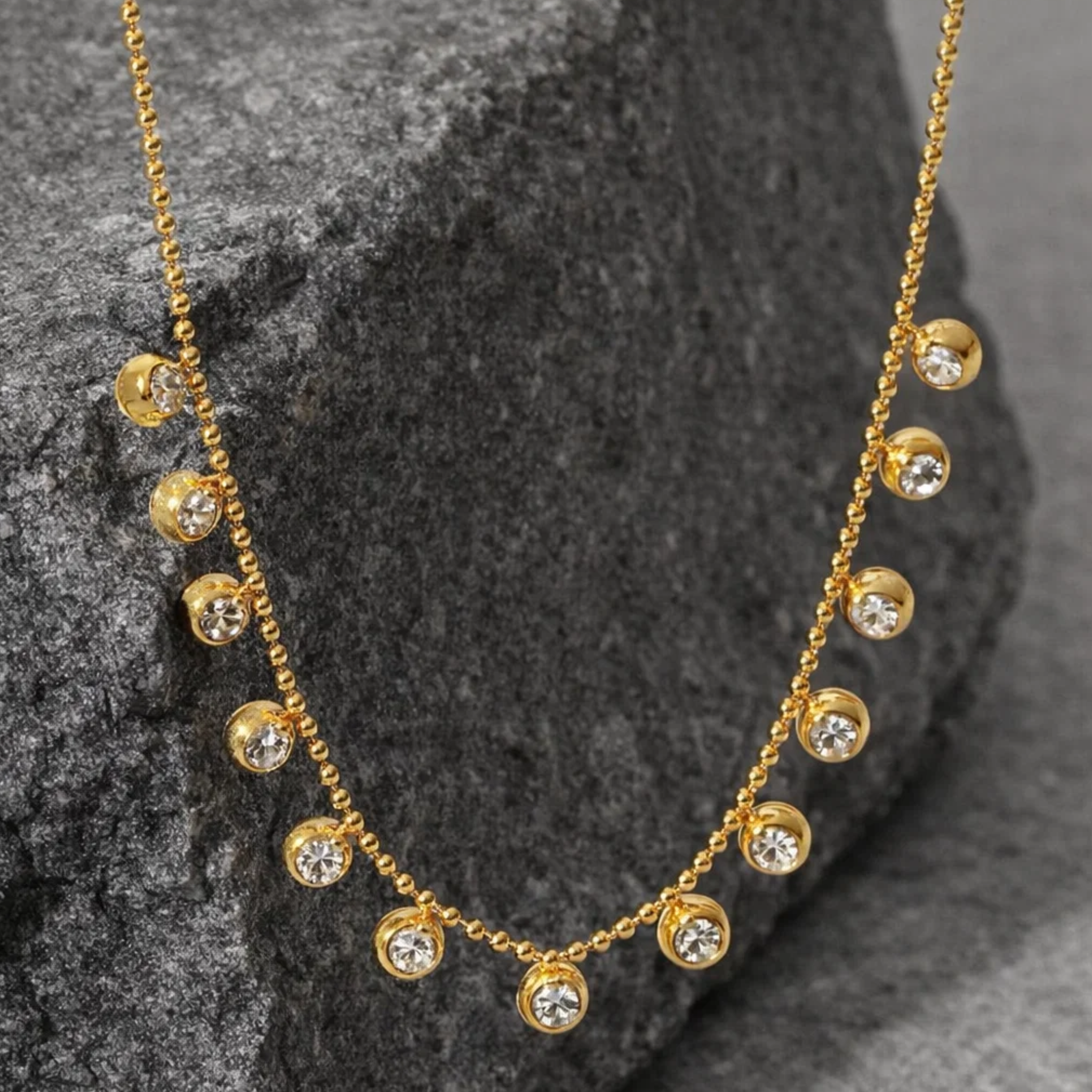 Gold necklace with diamond-like stones on a dark stone surface