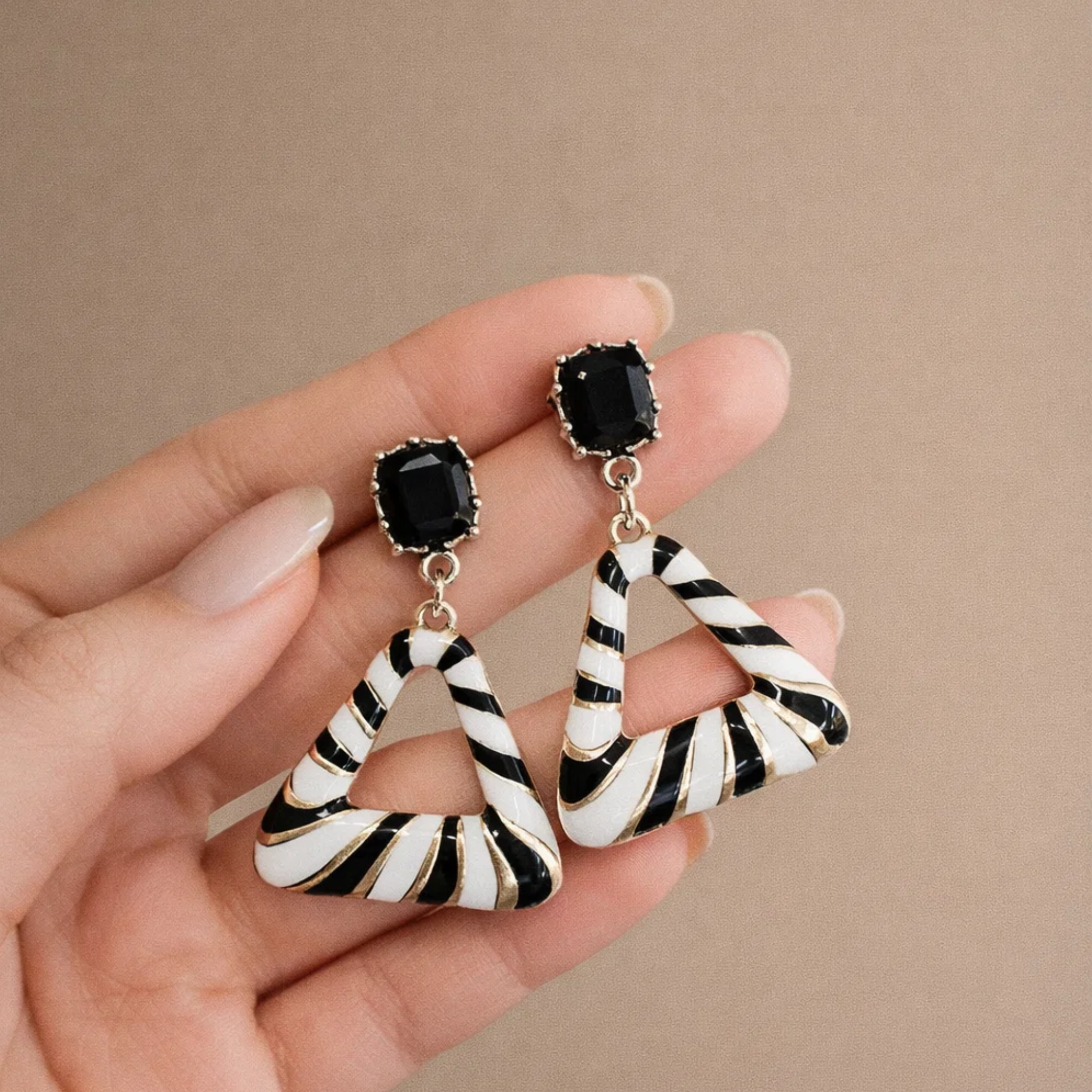 A woman holding triangle stripe earrings