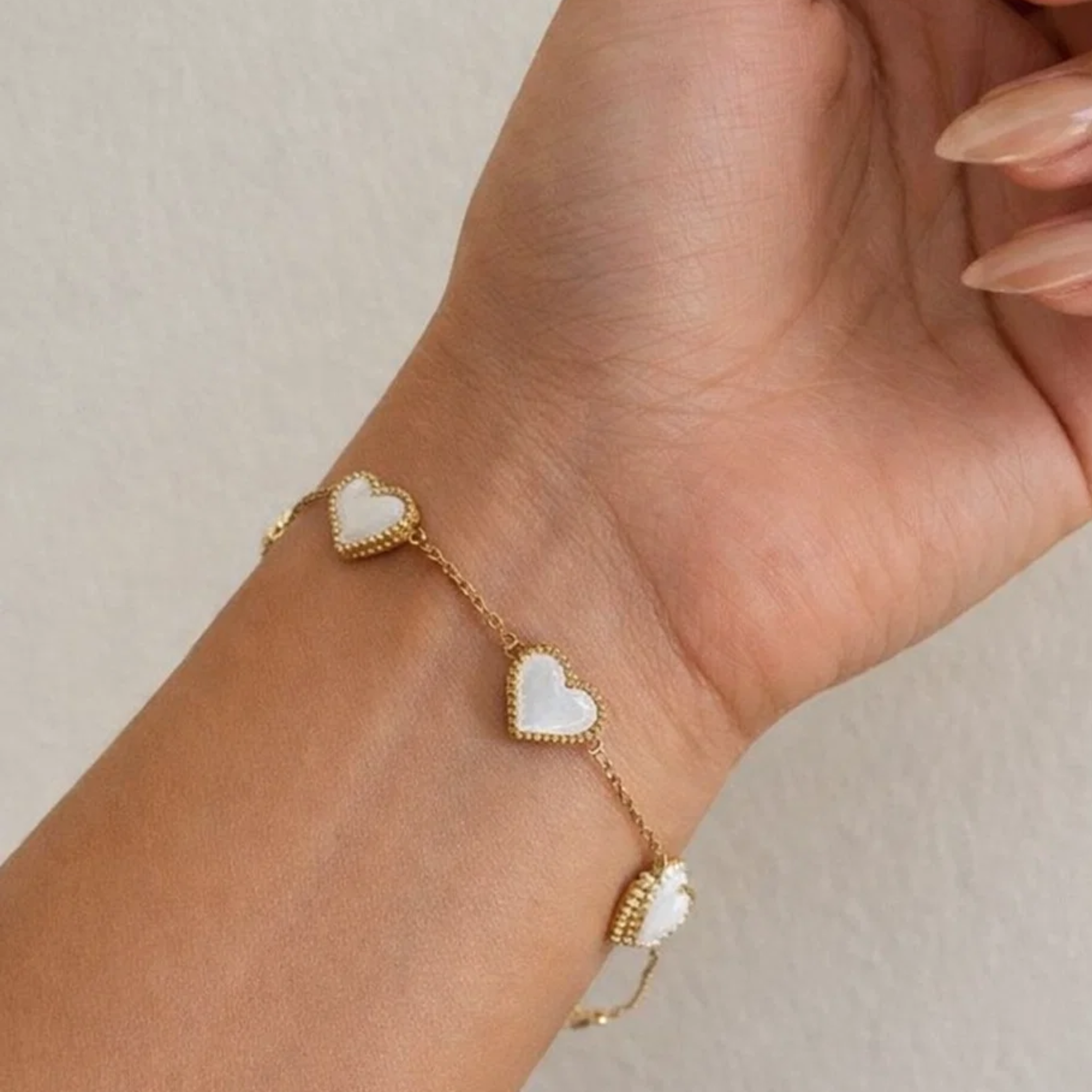 Gold bracelet with heart-shaped charms on a wrist 